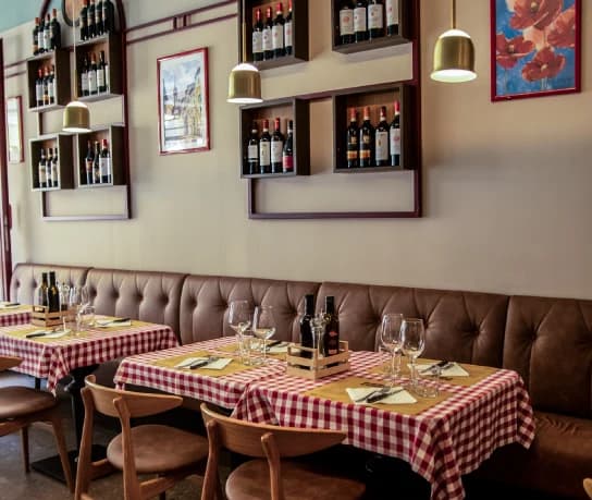 La sala dell’Osteria Le Pietre, con tavoli a quadretti e bottiglie di vino